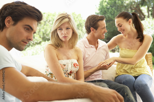 Couple With Problems Amongst Group Of Friends Relaxing On Sofa