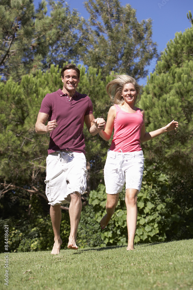 Fototapeta premium Young Couple Running Through Summer Field