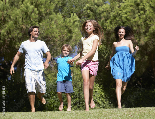 Young Family Running Through Summer Field