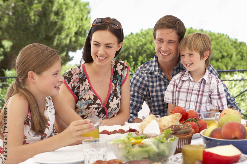 Young Family Enjoying Outdoor Meal Together