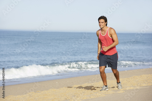 Young Man Jogging Along Beach