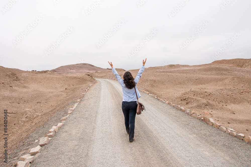 Young woman walking in the road with raised arms Young woman walking in the road with raised arms