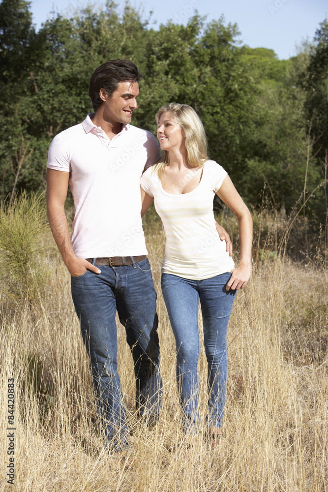 Young Couple Walking Through Summer Countryside Young Couple Walking Through Summer Countryside