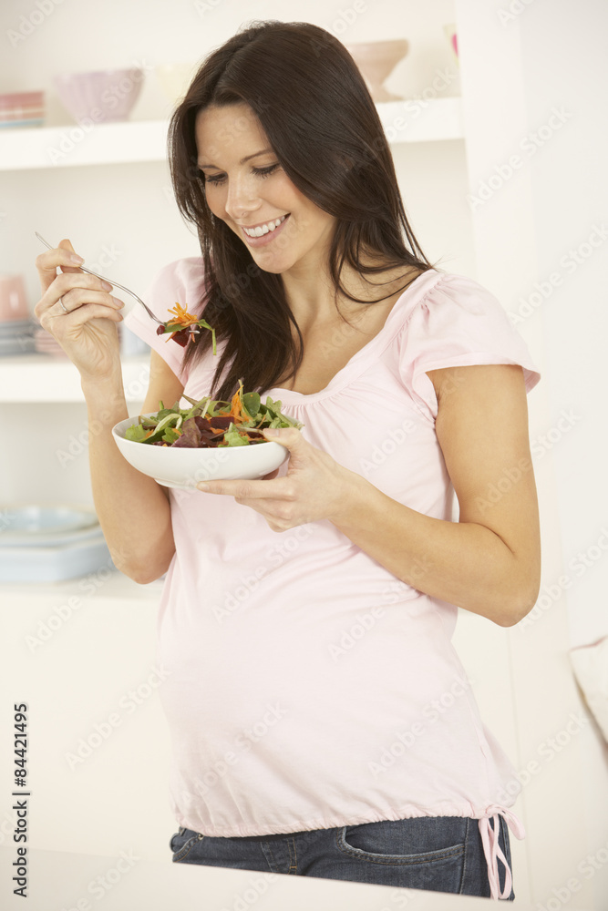 Pregnant Woman Eating Salad In Kitchen At Home Pregnant Woman Eating Salad In Kitchen At Home