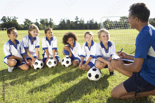 Group Of Children In Soccer Team Having Training With Coach photo