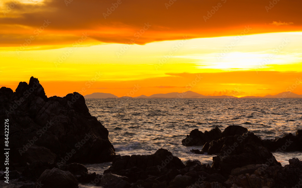 Beautiful sunset over the sea with silhouette of rock