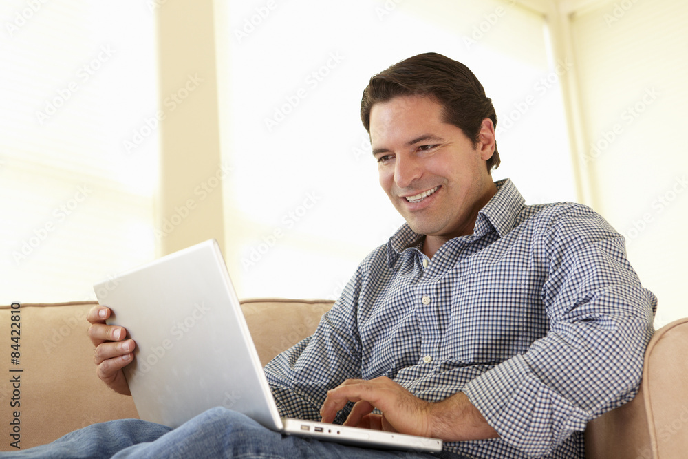 Hispanic Man Using Laptop At Home Hispanic Man Using Laptop At Home