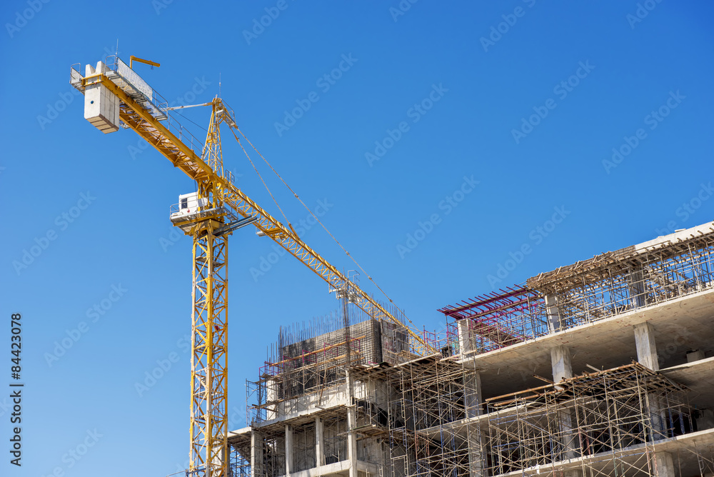 Hospital building under construction with cranes against a blue sky.