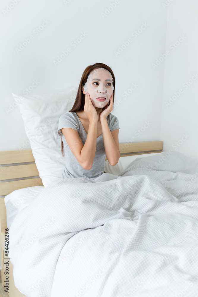 Asian woman using the paper mask and sitting on bed Asian woman using the paper mask and sitting on bed