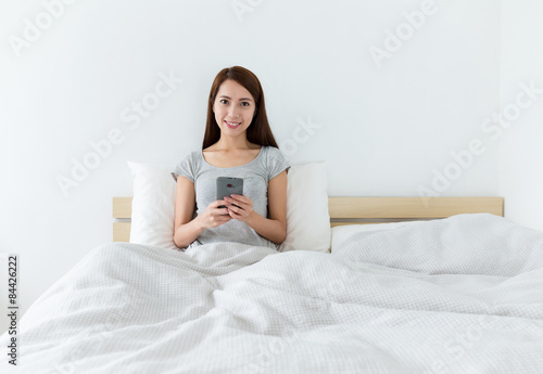 Asian young woman using cellphone on bed