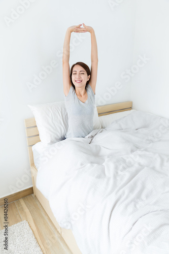 Young girl sitting on bed and hand raised up