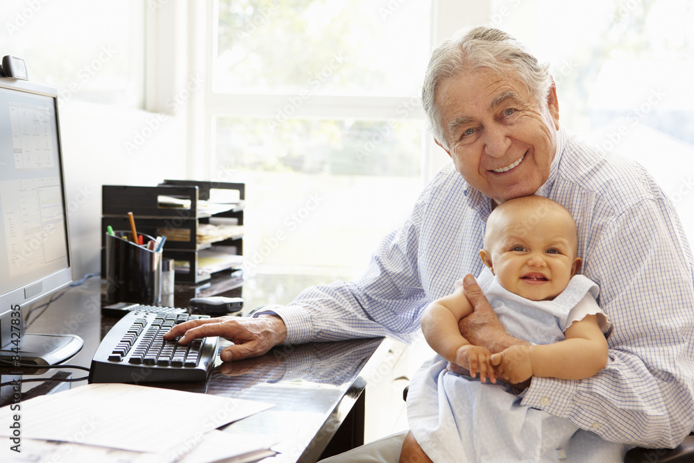 Senior Hispanic man with computer and baby Senior Hispanic man with computer and baby