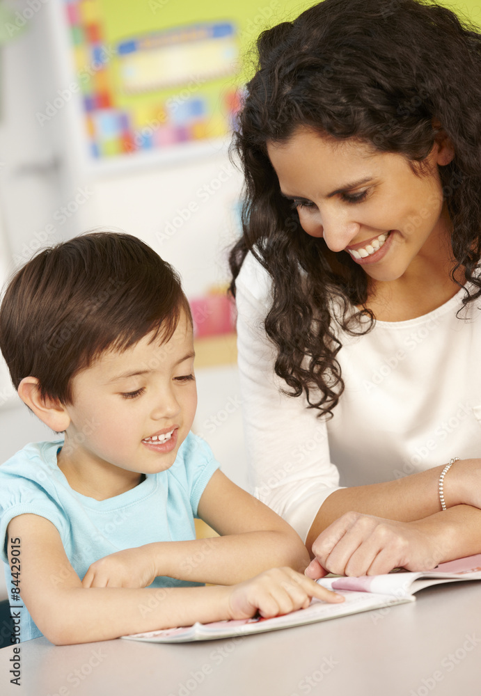 Elementary Age Schoolgirl Reading Book In Class With Teacher Elementary Age Schoolgirl Reading Book In Class With Teacher