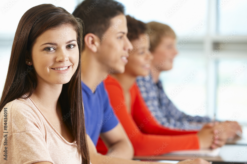 Multi racial teenage pupils in class, one smiling to camera