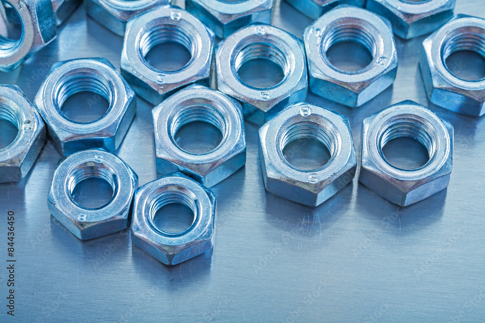 Close-up view of screw nuts on metallic background construction Close-up view of screw nuts on metallic background construction