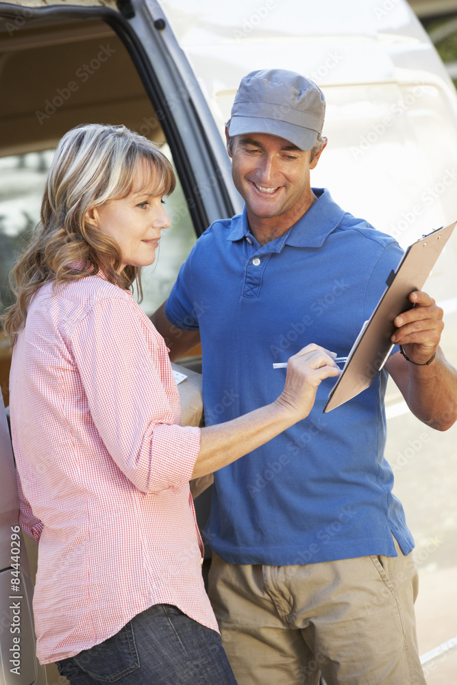 Woman Signing For Packager Delivered By Courier Woman Signing For Packager Delivered By Courier