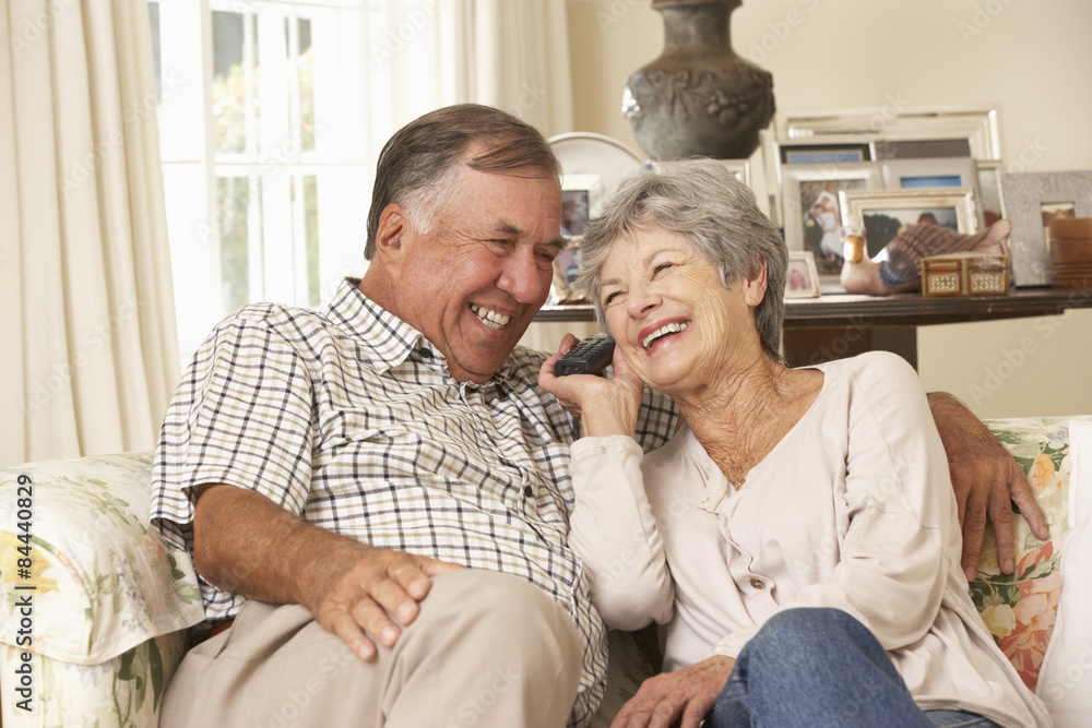 Retired Senior Couple Sitting On Sofa Talking On Phone At Home Together Retired Senior Couple Sitting On Sofa Talking On Phone At Home Together