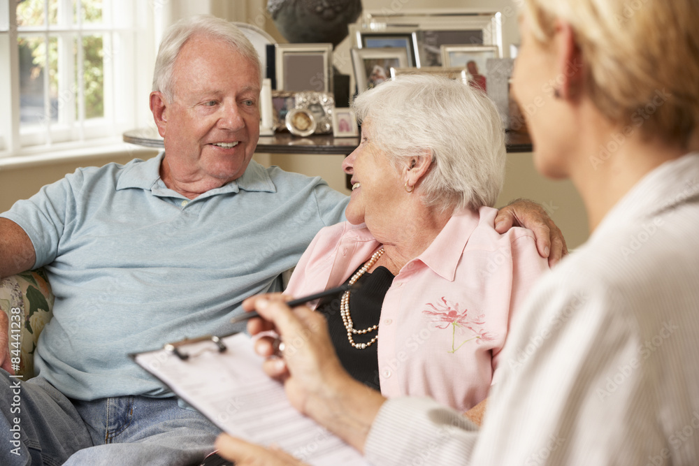 Obraz premium Retired Senior Couple Sitting On Sofa Talking To Financial Advisor