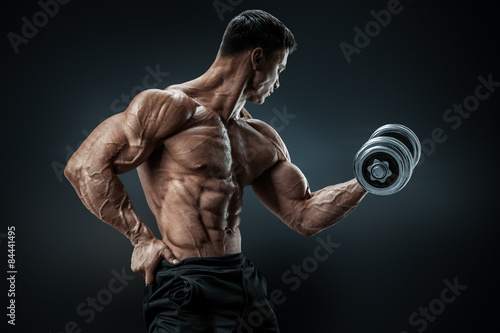 Power athletic man bodybuilder doing exercises with dumbbell photo
