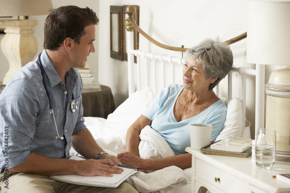 Doctor Talking With Senior Female Patient In Bed At Home Doctor Talking With Senior Female Patient In Bed At Home