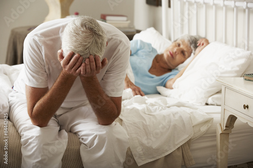 Quadro su tela Worried Senior Man Sits On Bed Whilst Wife Sleeps