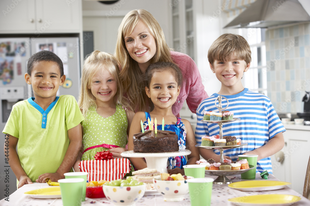 Group Of Children Standing With Mother By Table Laid With Birthday Party Food Group Of Children Standing With Mother By Table Laid With Birthday Party Food