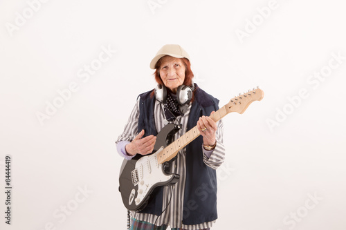 Funny elderly lady playing electric guitar.