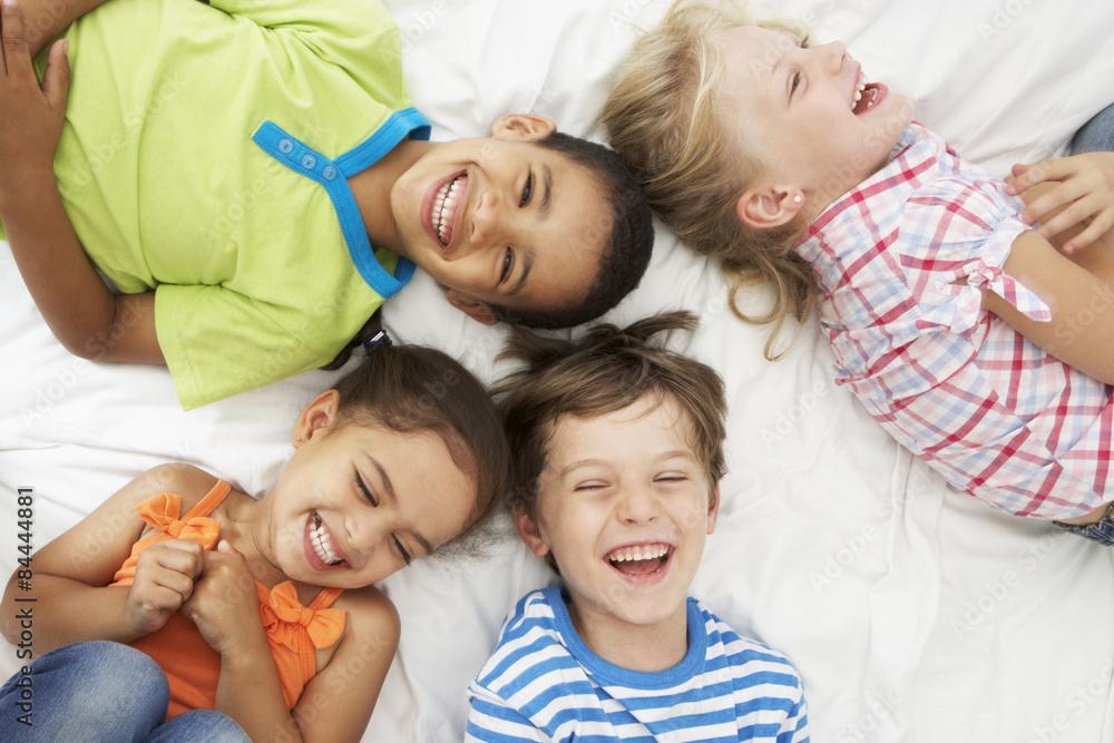Overhead View Of Four Children Playing On Bed Together Overhead View Of Four Children Playing On Bed Together