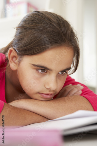 Bored Young Girl Doing Homework At Desk In Bedroom