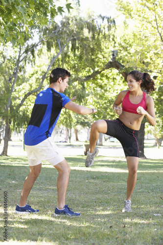 Young Woman Working With Personal Trainer In Park