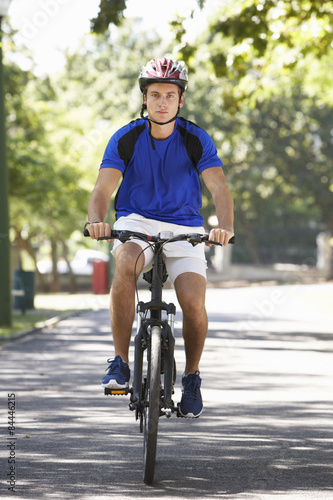 Young Man Cycling Through Park