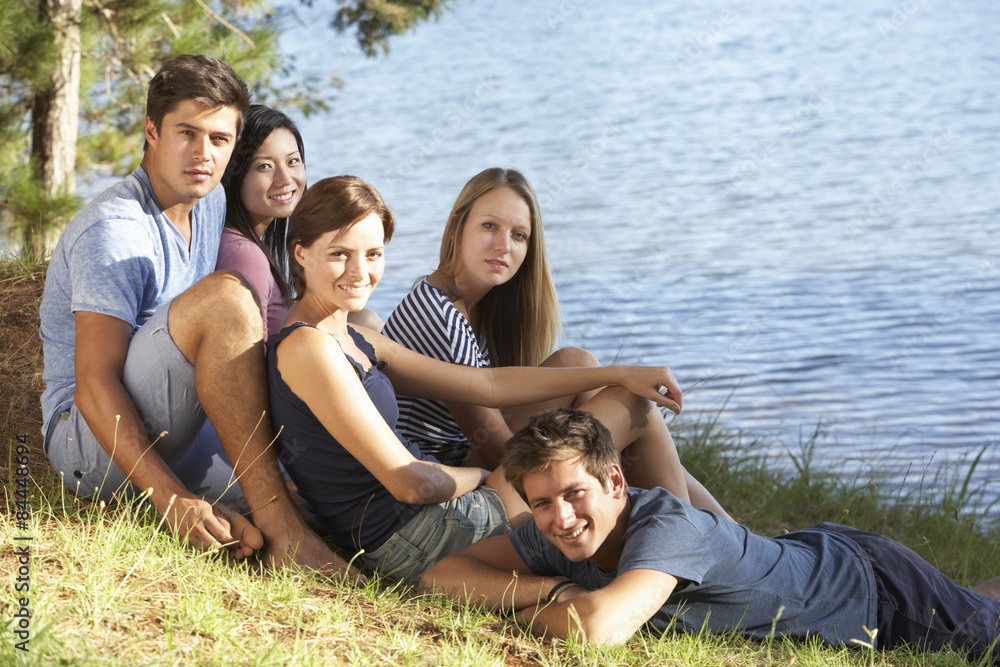 Group Of Young People Relaxing At Shore Of Lake