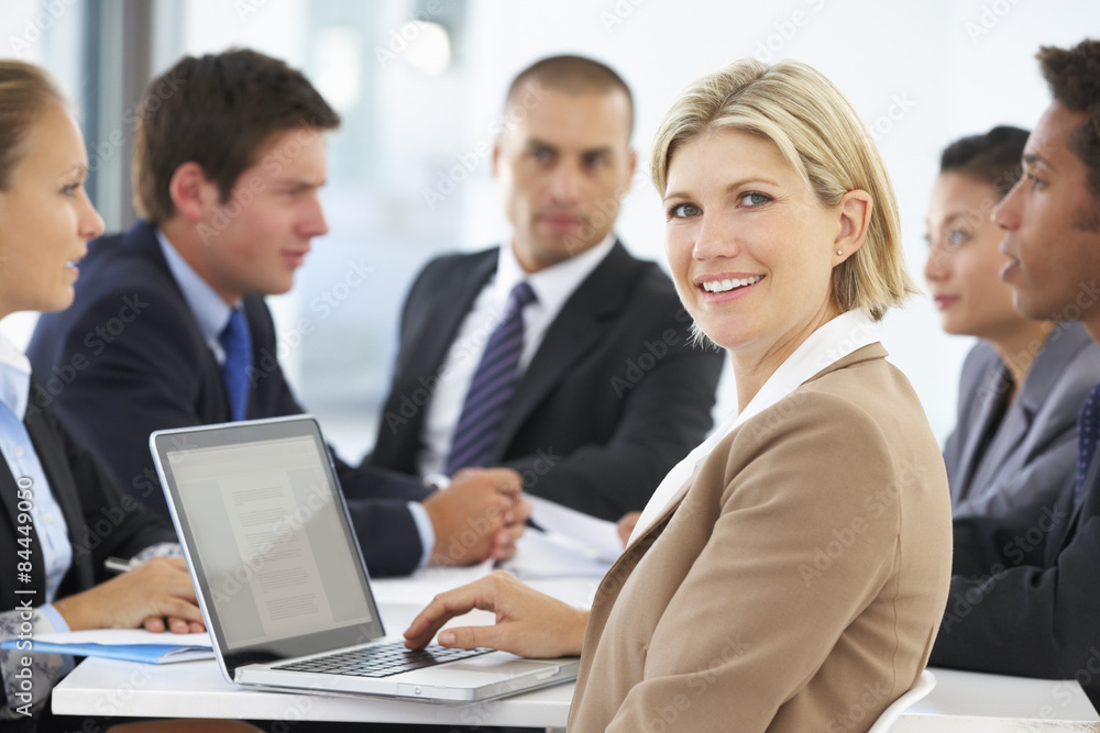 Portrait Of Female Executive With Office Meeting In Background Portrait Of Female Executive With Office Meeting In Background
