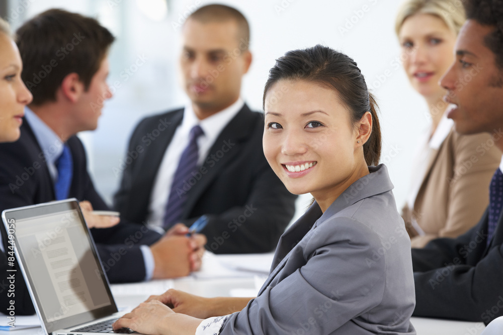 Portrait Of Female Executive With Office Meeting In Background Portrait Of Female Executive With Office Meeting In Background