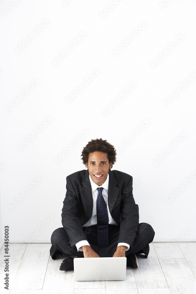 Studio Portrait Of Businessman Sitting On Floor Using Laptop Studio Portrait Of Businessman Sitting On Floor Using Laptop