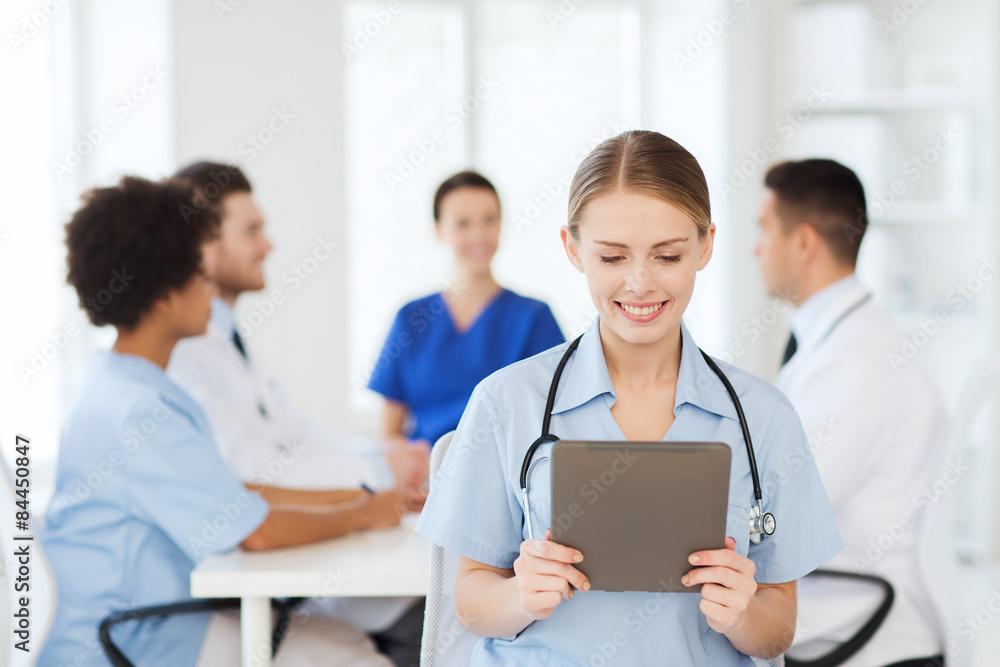 happy doctor with tablet pc over team at clinic