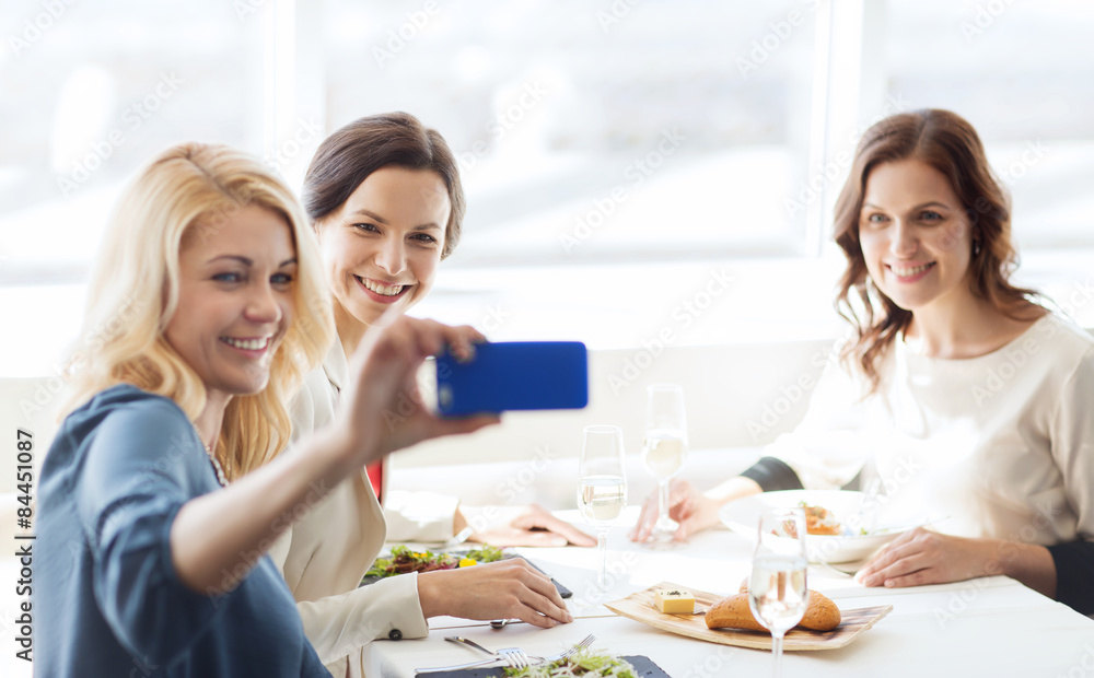 women with smartphone taking selfie at restaurant