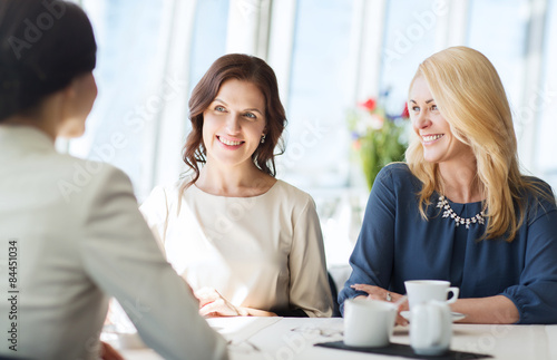 women drinking coffee and talking at restaurant