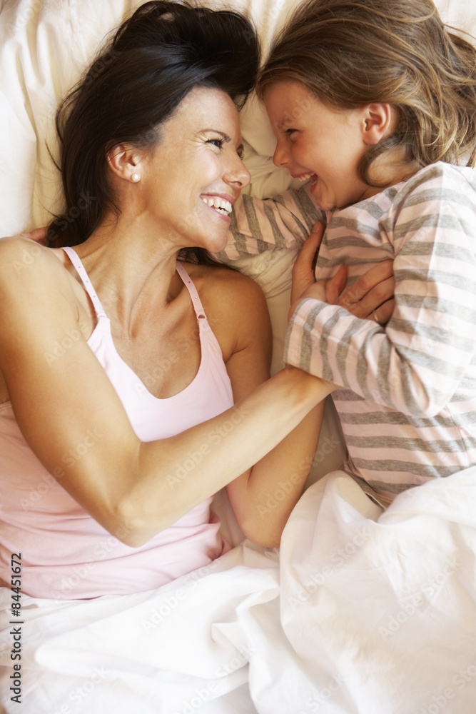 Mother And Daughter Relaxing In Bed