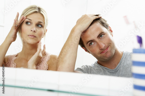 Couple Looking At Reflections In Mirror For Signs Of Ageing