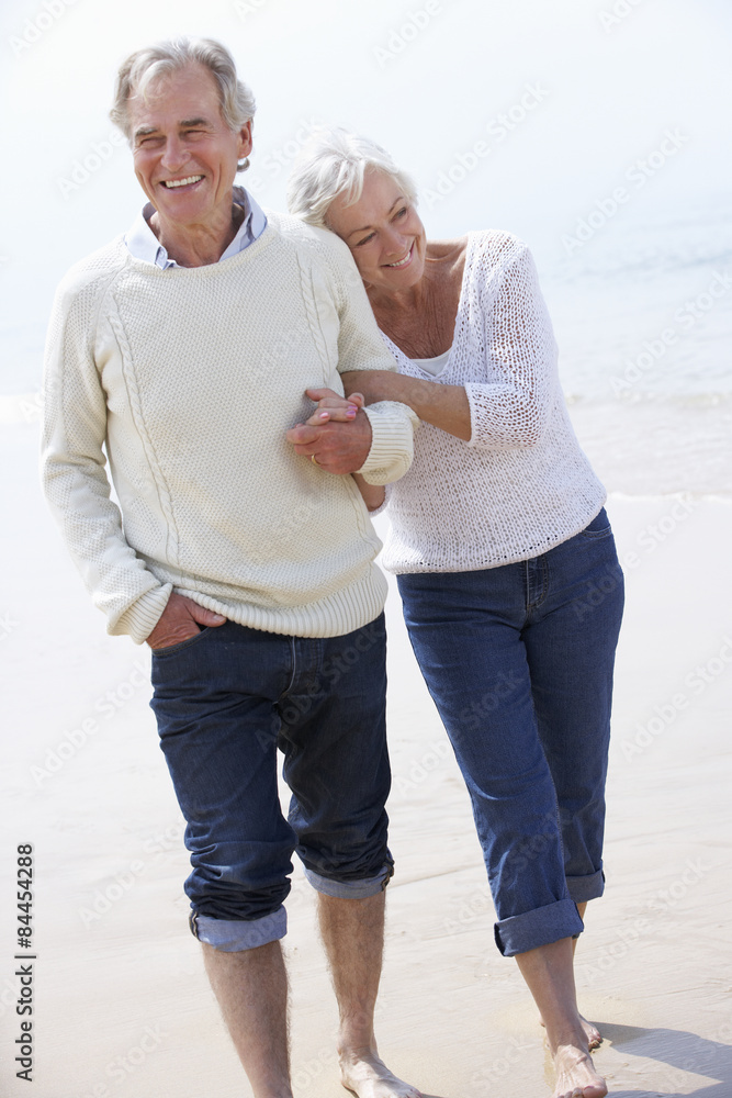 Senior Couple Walking Along Beach Together