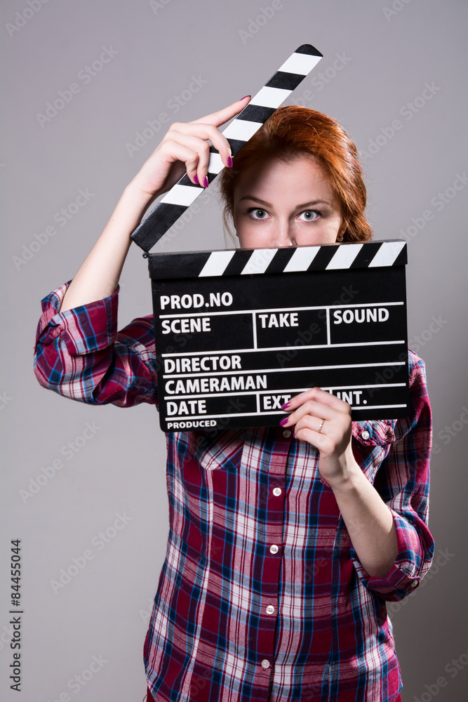 Obraz premium Beautiful red-haired woman holding a movie clapper, isolated ove