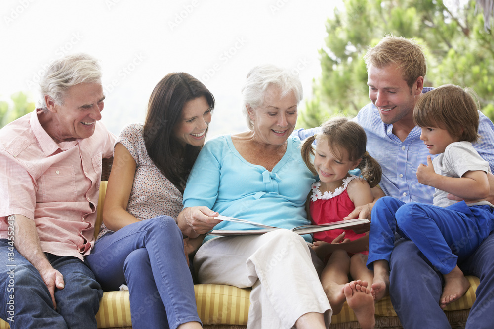 Multi Generation Family Reading Book On Garden Seat Multi Generation Family Reading Book On Garden Seat