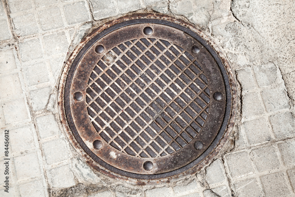 Round rusted hatch in urban pavement Round rusted hatch in urban pavement