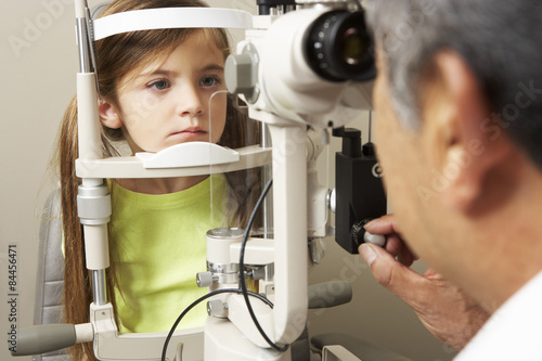 Optician In Surgery Giving Girl Eye Test