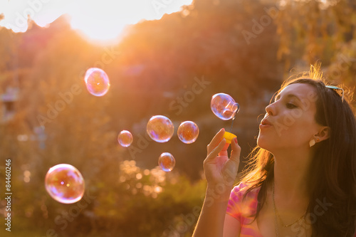 girl blowing soap bubbles at sunset