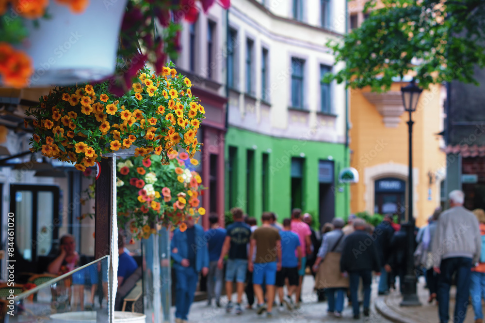 Tourists walking along the street of the old town with flowers i