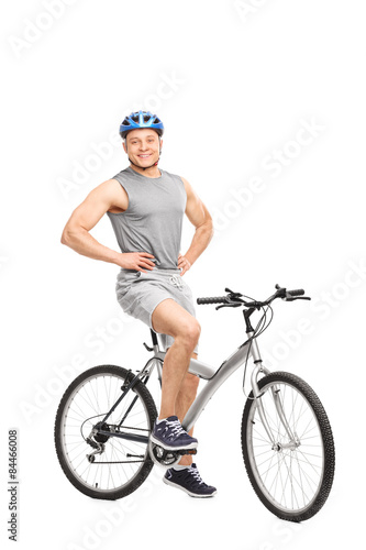 Young man posing seated on a bicycle