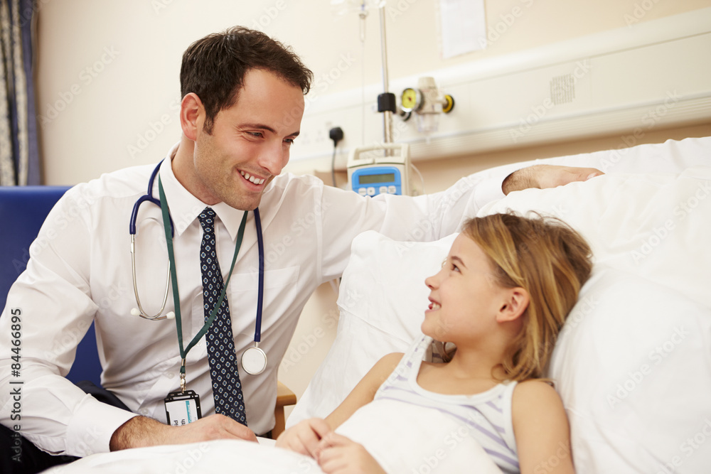 Doctor Sitting By Young Girl's Bed In Hospital Doctor Sitting By Young Girl's Bed In Hospital