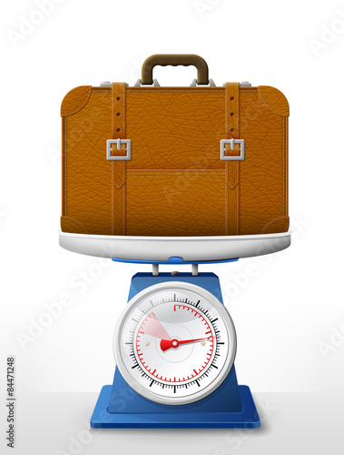 Leather suitcase on scale pan. Weighing travel bag with belts